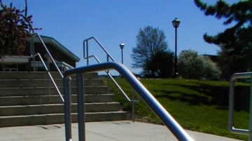 Stairway and railing walking up to the Etown College Gym, next to an ornamental conifer, with a flowering ping tree in full bloom at the top